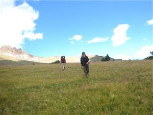 two people walking in grass with blue sky